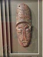 Close-up photo of the textured carved mask showing facial features and forehead ridges.