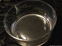 Photo of clear, heavy crystal bowl by Rosenthal with smooth design and polished finish on dark cloth background.