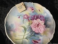 Full view of one hand painted plate with soft pastel background and detailed floral painting.
