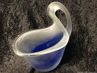 Side view showing pitcher form, curved handle, matte clear textured outer surface, and shiny blue interior.