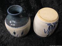 Photo showing two Indigenous art pottery vases, one blue glazed with painted designs and one cream-colored with blue painted abstract art and signed base.