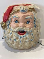 Front view showing painted Santa Claus face with a crack on the forehead and chipped paint on the hat's edge.