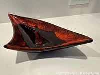 Side and angled view of the large ceramic ashtray showing glossy orange and black leaf pattern with sharp angular atomic design