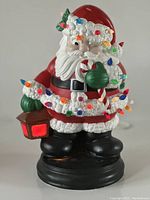 Front view of the 1982 Atlantic Mold Winking Santa ceramic figurine, showing Santa holding a lantern and wrapped in colorful Christmas lights.