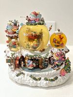 Front view of the triple Christmas snow globe showing the three snow globes, snowmen, and snowy village base with painted details and glitter inside the globes.