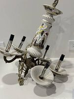 Chandelier with visible porcelain and metal arms, hand-painted details, with candle light bulb holders and chain for hanging.