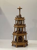 Full view of the four-tier wooden nativity pyramid carousel, showing overall shape and structure.