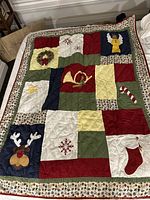Full view of the handmade Christmas quilt with various holiday applique patches in a patchwork design.