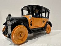 Front and left side view of the vintage cast iron toy yellow cab, showing driver figure and yellow wheels.