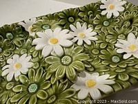 Close-up view of the tray to show the textured daisies in white and green with yellow centers, highlighting the craftsmanship and color details of the ceramic piece.