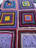 Close-up image of vibrant crochet squares in multiple colors showing the detailed crocheted pattern and color variations.