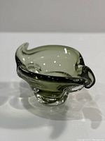 Front angled view of olive green freeform glass catchall with curved rim extensions.