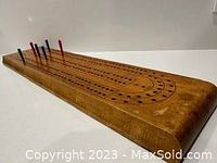 Vintage wooden cribbage board displaying the full length and surface, brown wood with drilled peg holes, slight wear visible