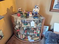 View of the entire collection of animal figurines inside and on top of a glass display cabinet, showing various dogs, cats, and other animals