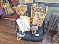 View of the full lot including Boston Bruins tote bag, teddy bear in hockey gear, and two autographed Bobby Orr photos on a chair.