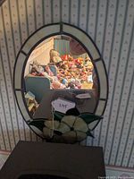 Full view of oval stained glass mirror with reflection showing room background.