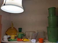 Vintage kitchenware collection arranged on shelf showing various measuring spoons, cups, and containers