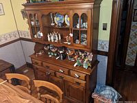 Full view of solid wood rock maple dining room hutch with contents shown inside but not included in the lot. Hutch features multiple shelves, cabinet doors, drawers, and brass hardware.