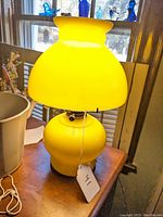 Yellow glass electric table lamp viewed from front showing shade and base with pull chain and tag number 41.