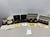 Wide view of six Highland Mint cases containing individual and multi-medallion sets