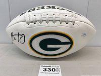 Full side view of white panel football with autograph and Packers logo