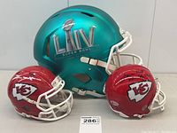 Overview of lot with full-size commemorative helmet and two mini Chiefs helmets