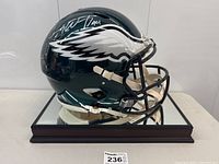 Angled right-side view of full-size Eagles helmet on mirrored wooden base, showing wing decal and right-side autograph.