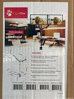 Close-up of product specifications and features on box label, showing dual monitor stand with adjustable arms and mounting options.