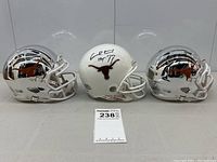 Three Riddell mini helmets (two chrome, one white) with Texas Longhorns logos