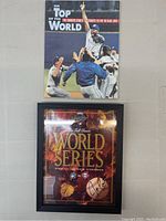 Both items displayed flat: tribute book above and framed scorebook below