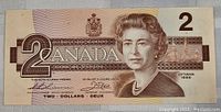 Front side of the 1986 Canadian two dollar bill showing the large '2', 'Canada' text, and portrait of Queen Elizabeth II.