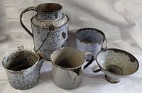 Front view of all five enamelware kitchen pieces showing wear and patina