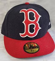 Front view showing navy blue fitted cap with red brim, Boston Red Sox logo, size sticker on brim