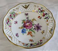 Top view showing central multicolored floral arrangement with lattice and gold rim.