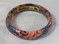 Photo showing the bracelet from the top angle revealing the floral pattern and label inside the bangle.