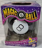 Photo showing front of Magic 8 Ball in purple branded box with window display.