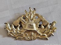 Close-up of firefighter helmet centered on metal badge, visible tarnish and wear.