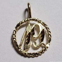 Close up photo of a 10K yellow gold pendant featuring the number 19 inside a twisted rope circular frame.