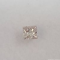 Close-up of the loose princess cut pink diamond on white surface.