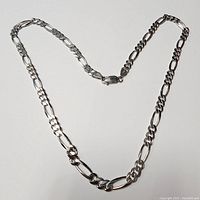 Full view of the sterling silver Figaro chain necklace laid out to show length and style.