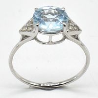 Front view of the ring showing the oval blue topaz gemstone alongside diamond accents on a rhodium plated silver band.