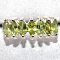 Close-up top view of the silver ring showing seven marquise-cut peridot stones set horizontally in a row. Stone color is light green.