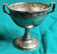 Front angle view of trophy showing overall shape, decorative band and patina