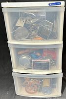 Full front view of the 3-drawer plastic organizer filled with various kitchen tools and gadgets