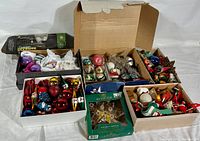 Overview of multiple boxes filled with vintage Christmas ornaments, including glass baubles in various colors, tinsel, and decorative holiday accessories.