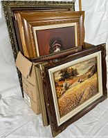 Side view of box containing multiple framed artworks, showing the variety of frames and art edges