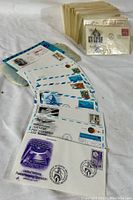 Close-up photo of assorted first day covers with airmail designs and commemorative postage stamps including themes like the United Nations Peacekeeping Operation and space exploration, arranged on a white surface.