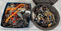 Top view of all jewelry items in a blue box and a brown basket, showing various necklaces, bracelets, watches, and costume jewelry pieces.