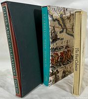 Side view showing the spines and slipcases of the three Folio Society books 'Cities and Civilisations', 'Mapping the World', and 'The First Colonists'.