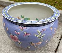 Angled side view of the vintage porcelain planter showing blue exterior with floral designs.